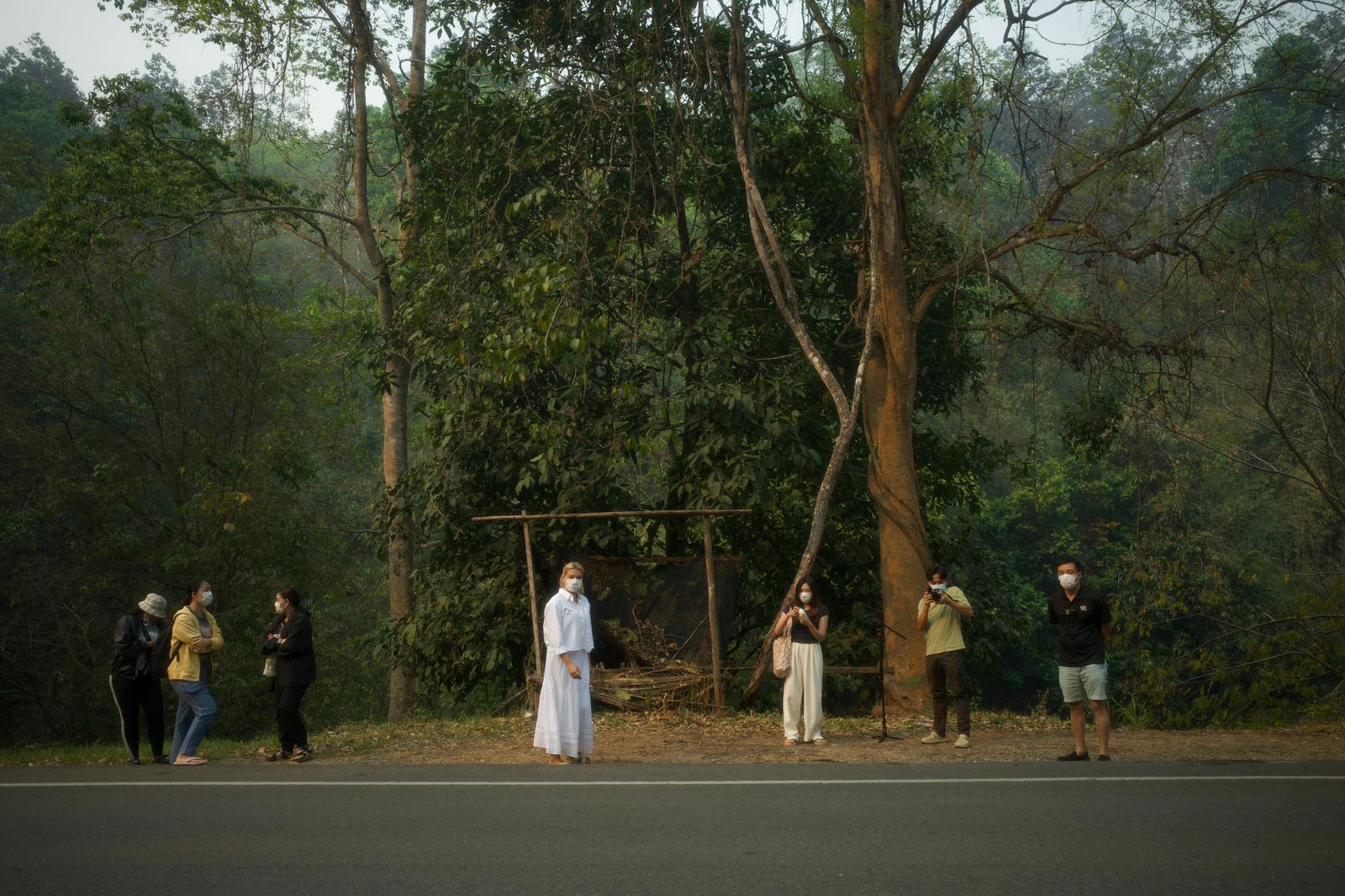 A roadside setup at the forest edge, the crew framing a portrait in the morning haze.