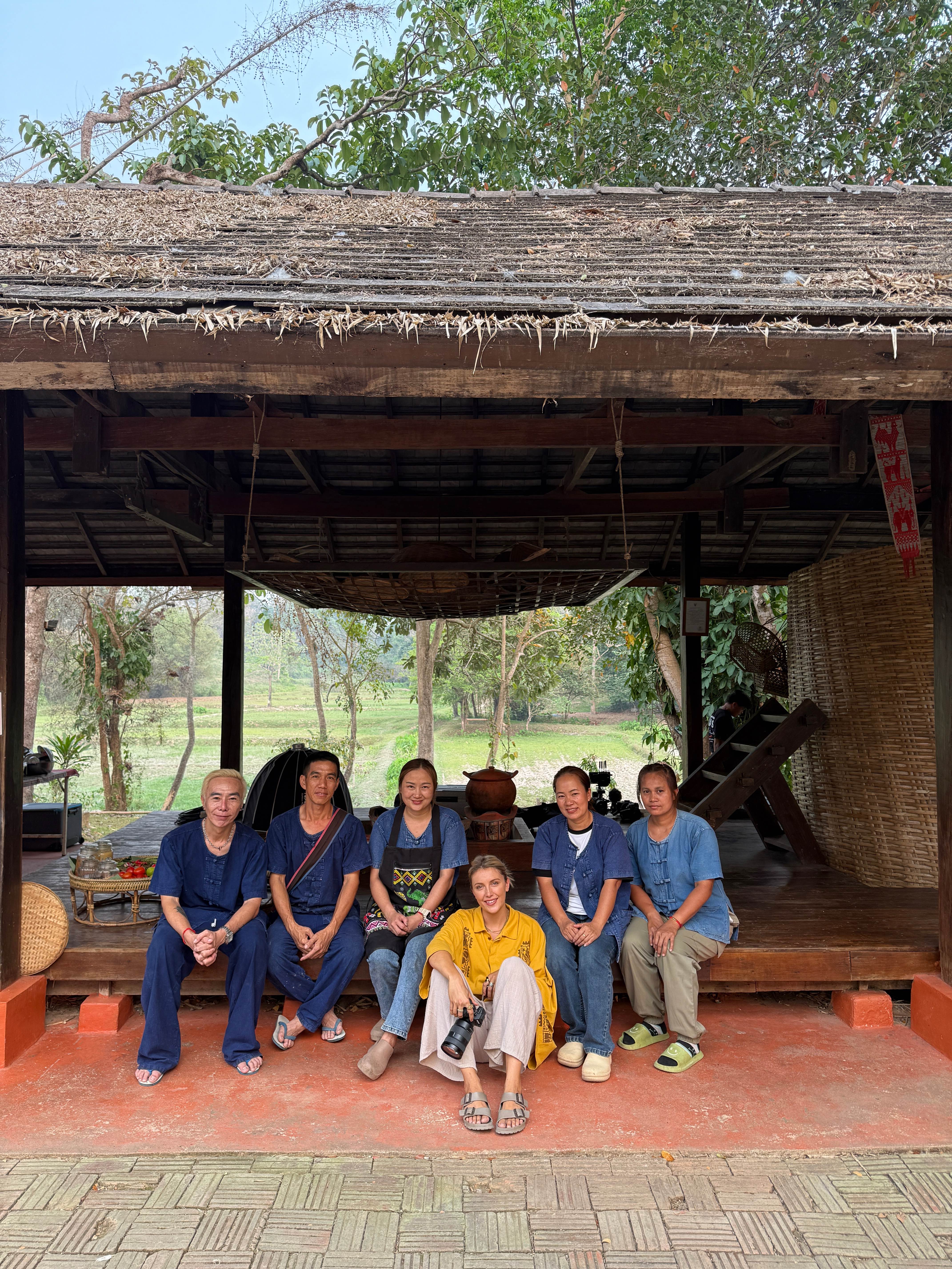 Anna with local practitioners under a wooden pavilion in a Thai village