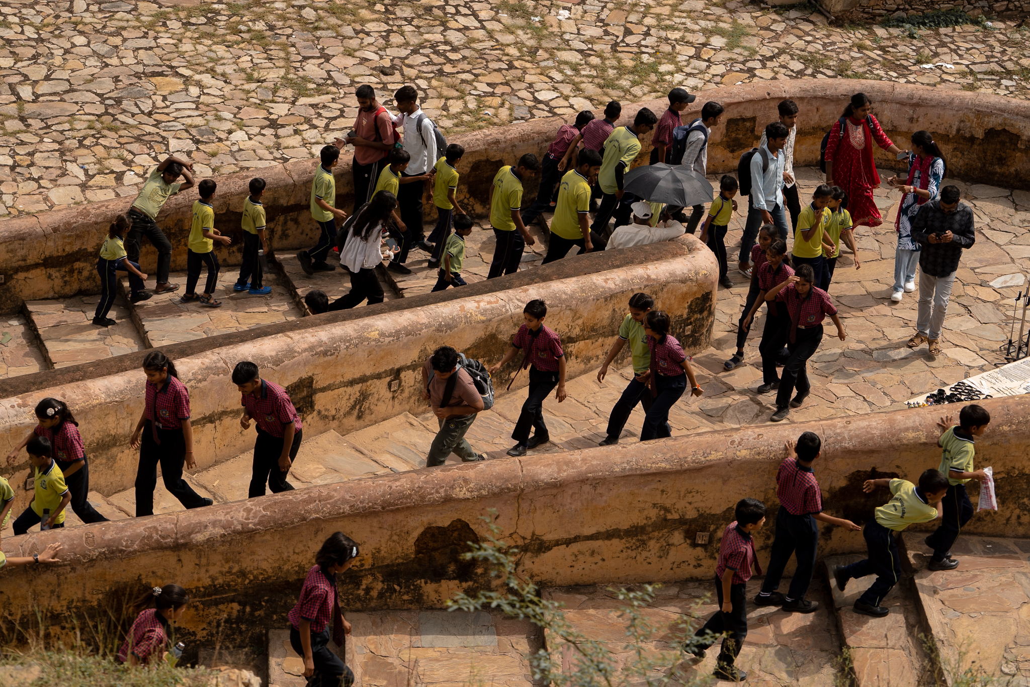 Schoolchildren in bright uniforms wind up the worn sandstone terraces of a centuries-old fort, a river of color across the stone.